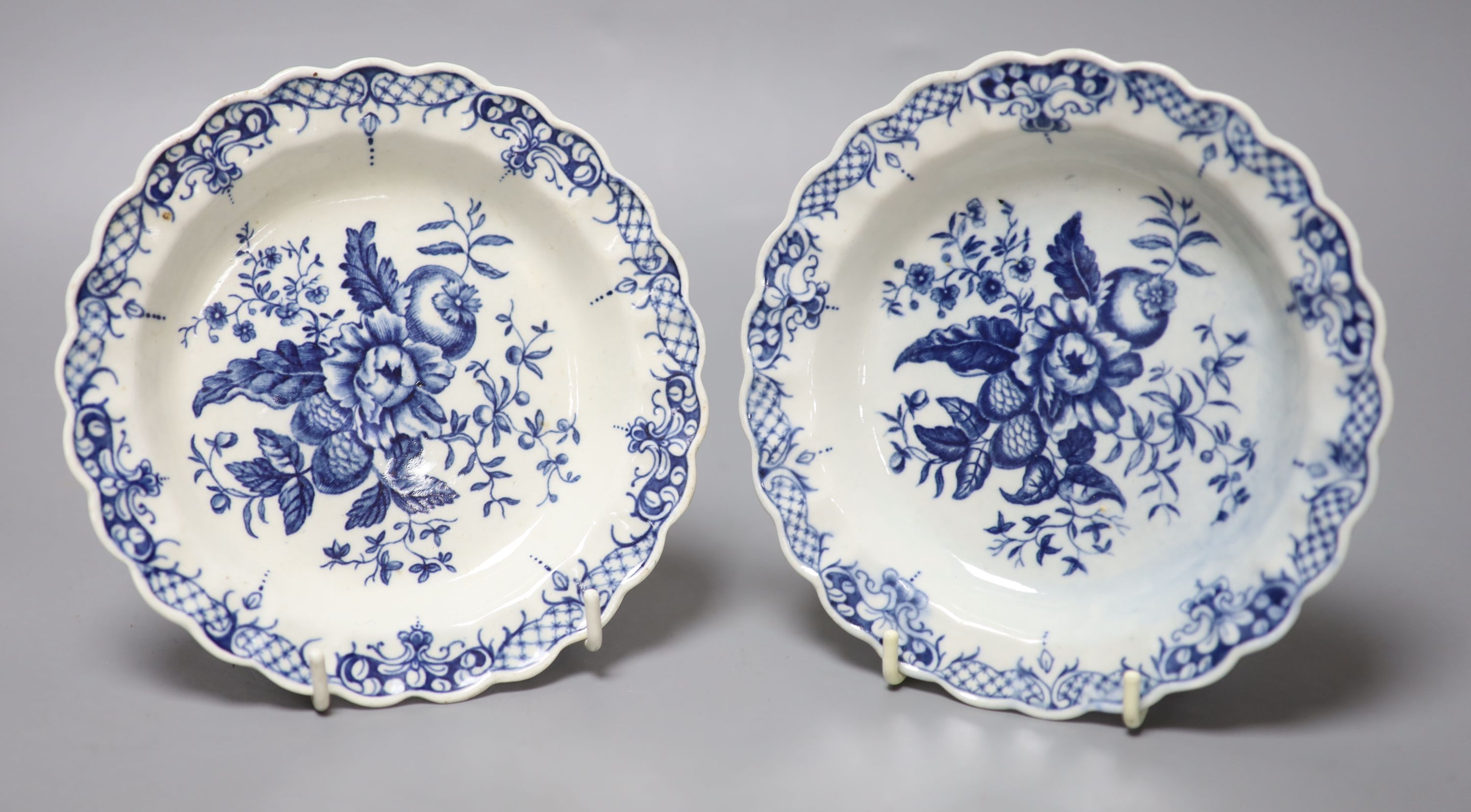 A pair of 18th century Worcester scalloped plates decorated with fir cones, flowers and a rose hip under an elaborate border, crescent